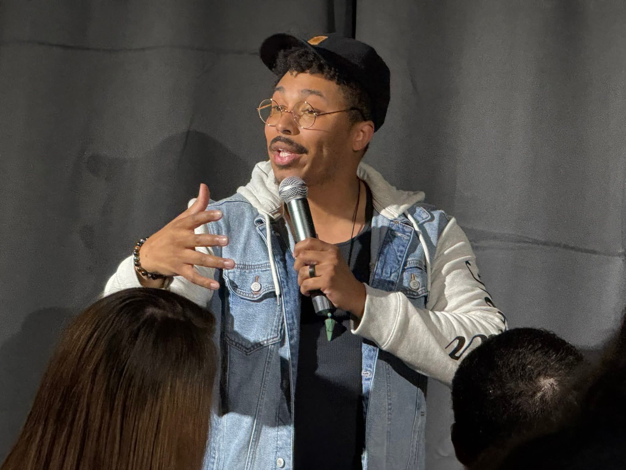 Jeremiah performing on stage in a denim vest with a microphone